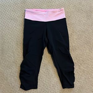 Lululemon black crop leggings with pink and white waistband detail. Size 4.